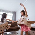 girl playing with cardboard toy airplane at home 2 Juegos con material reciclado para enseñar a los más pequeños