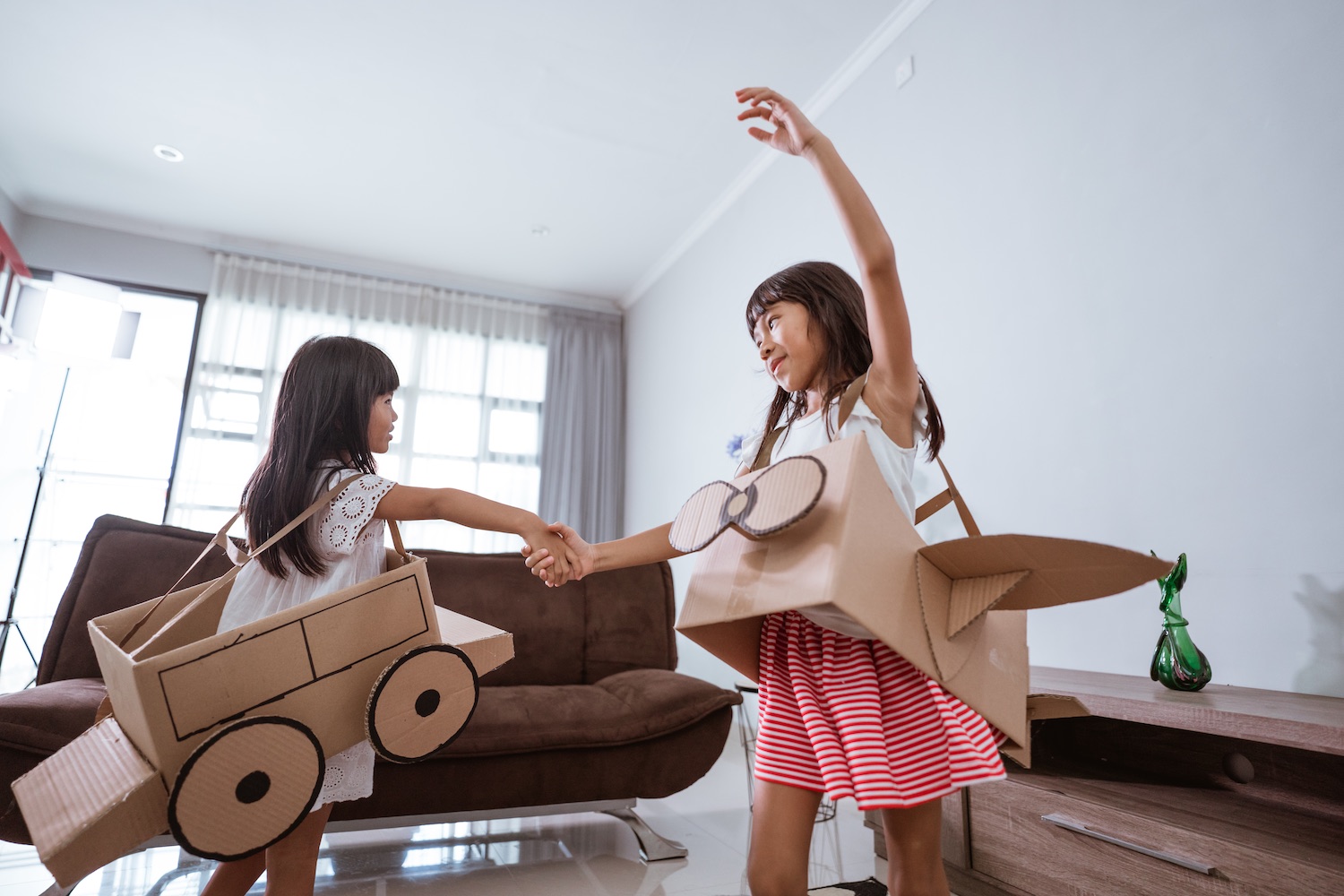 girl playing with cardboard toy airplane at home 2 Juegos con material reciclado para enseñar a los más pequeños